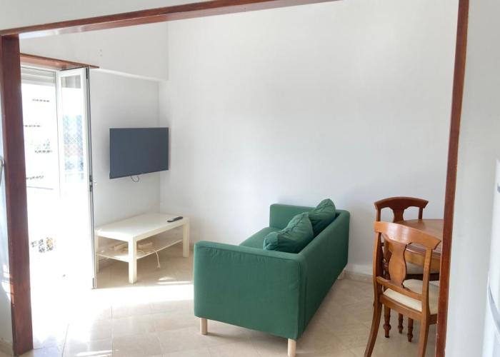 Sala com sofá, TV e zona de refeições