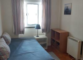 Quarto com cama individual, secretária, armários embutidos e televisão
