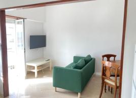 Sala com sofá, TV e zona de refeições