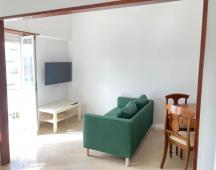 Sala com sofá, TV e zona de refeições